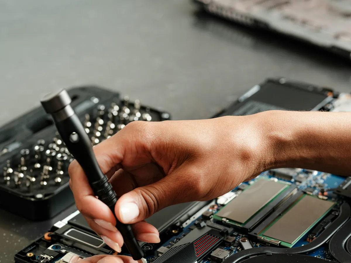 A technician working inside a laptop with a precision screwdriver