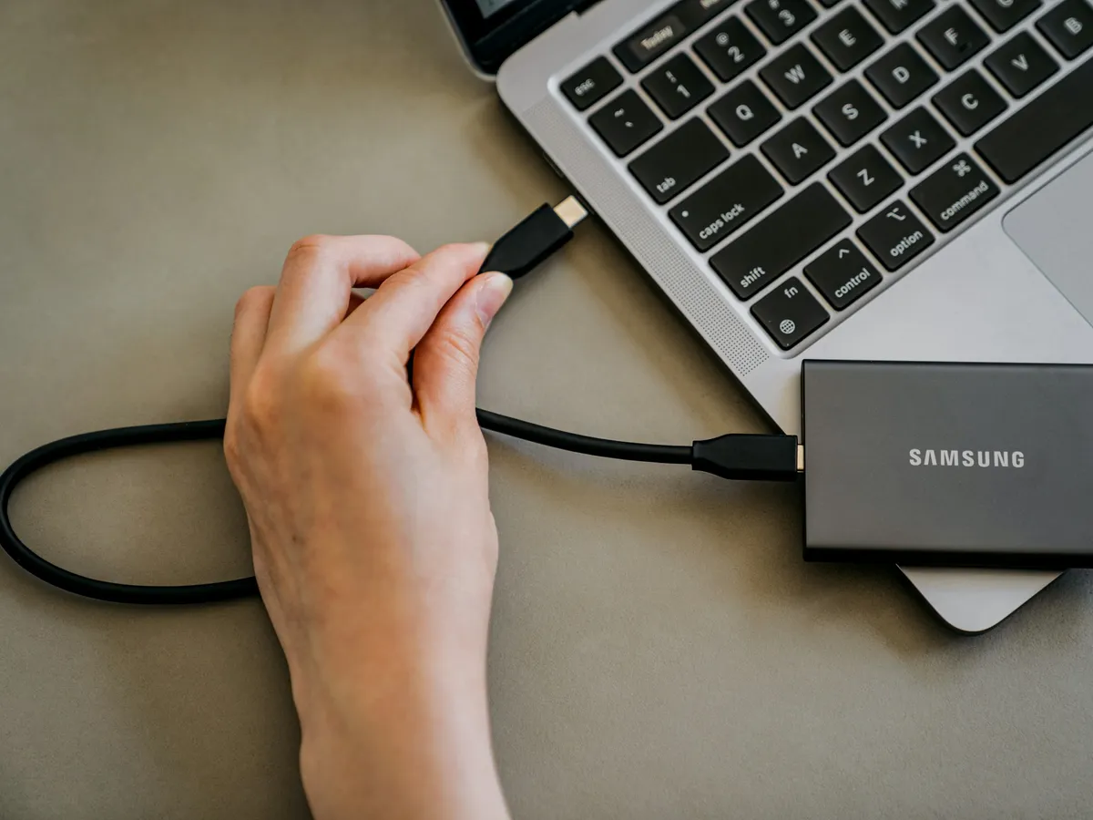 A portable drive being plugged into a laptop